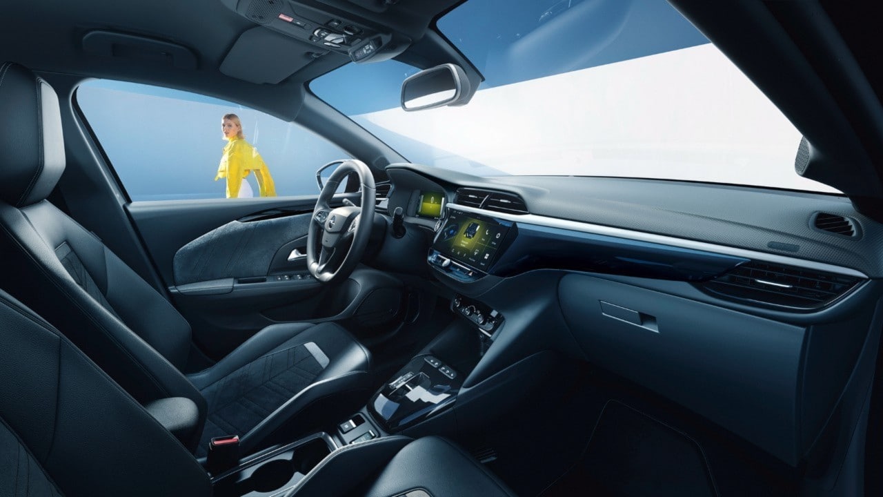 Opel Corsa Electric fekete belső tere oldalnézetből az utasülésből, sárga pólójú nővel a háttérben
