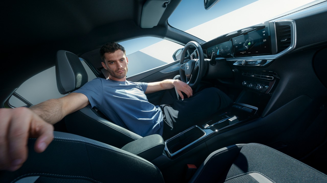 Man in driver seat of an Opel Mokka Electric looking at the passenger seat