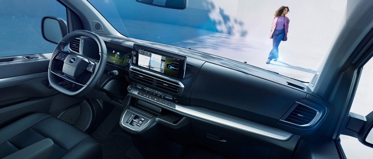 Egy fehér Opel Zafira Electric belső terének nézete az utasülésből, egy kint álló nővel